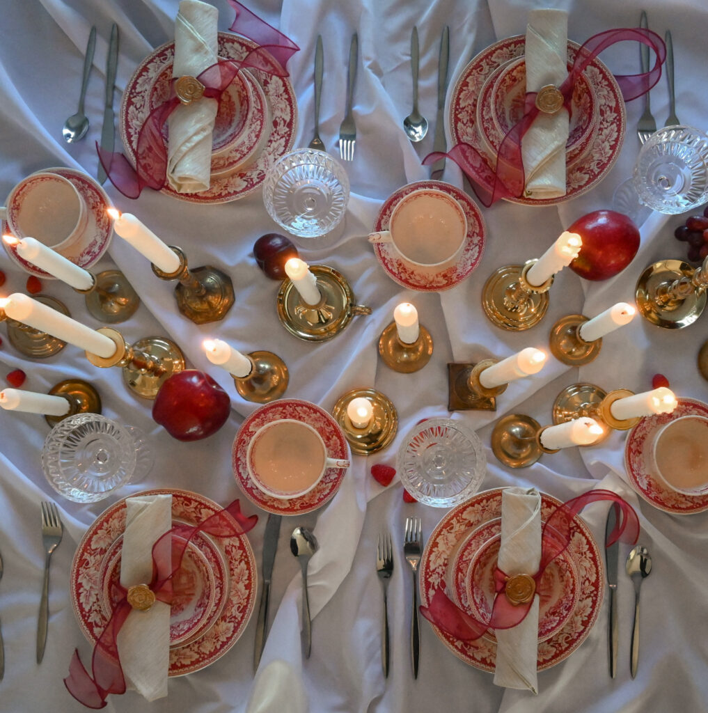 Table setting showing white tablecloth, plates, napkins, silverware, and candles