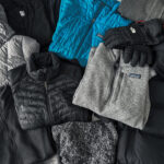 A collection of winter gear including hats, gloves, jackets, and fleeces