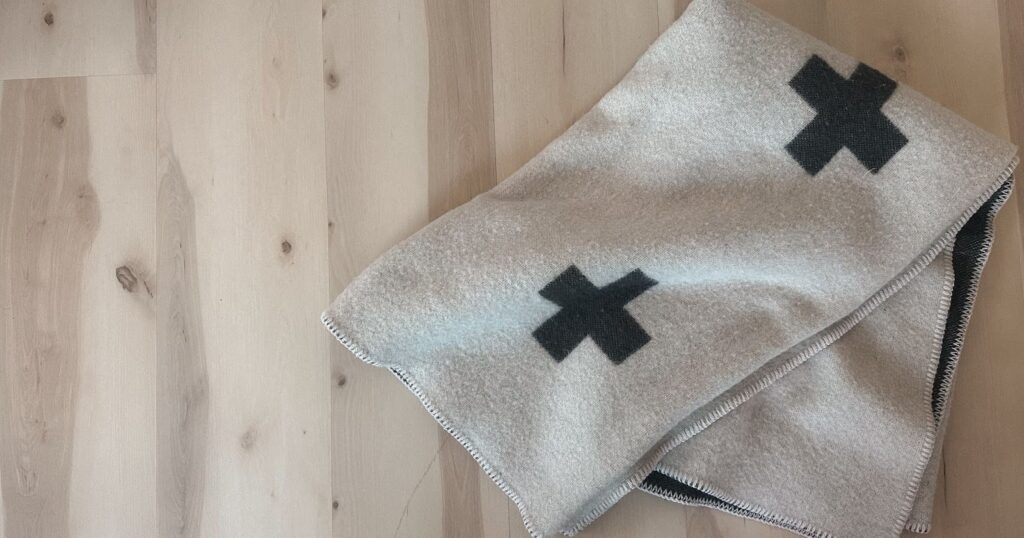 White wool throw blanket on light wood background