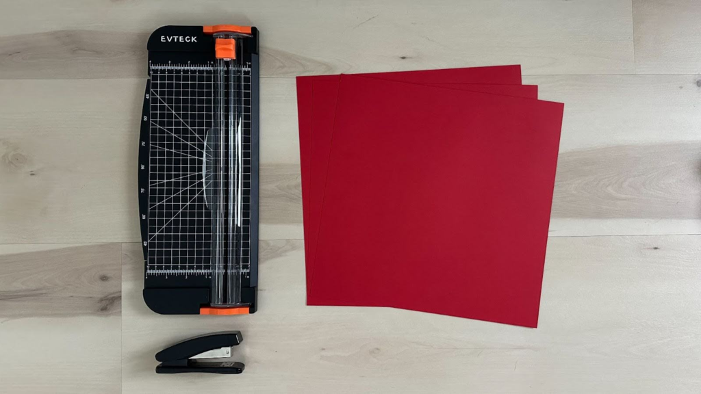 Paper cutter, red paper, and stapler on wood floor