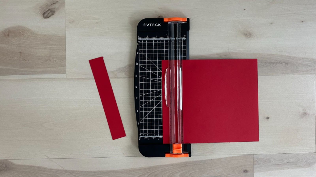 Paper being cut by paper cutter on wood floor