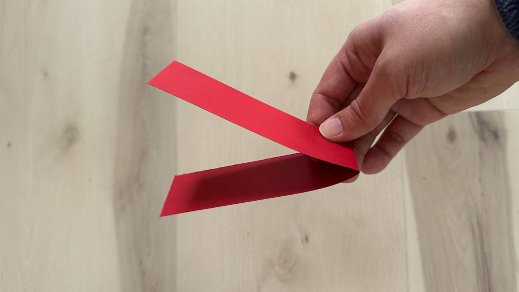 Hand holding a red piece of paper folded into a V-shape