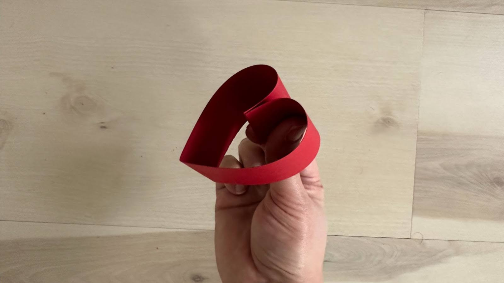 Hand holding red paper folded into a heart shape