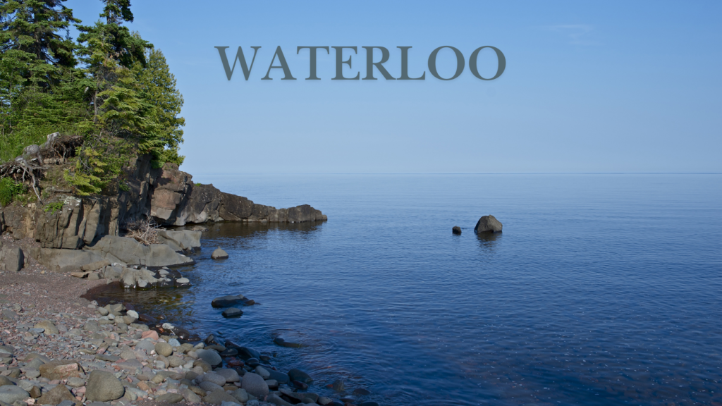 A rocky beach with trees and a deep blue lake
