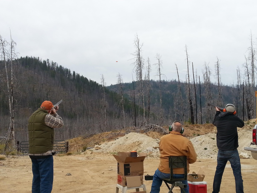 Three men aiming shot guns at a clay shooting range