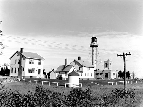 The white skeletal iron tower and red-roofed keeper's dwelling of the Whitefish Point Lighthouse on Lake Superior.