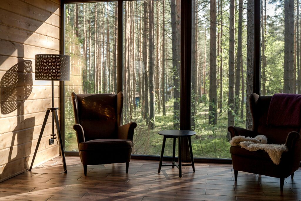 Two brown chairs sitting by a window in a cabin